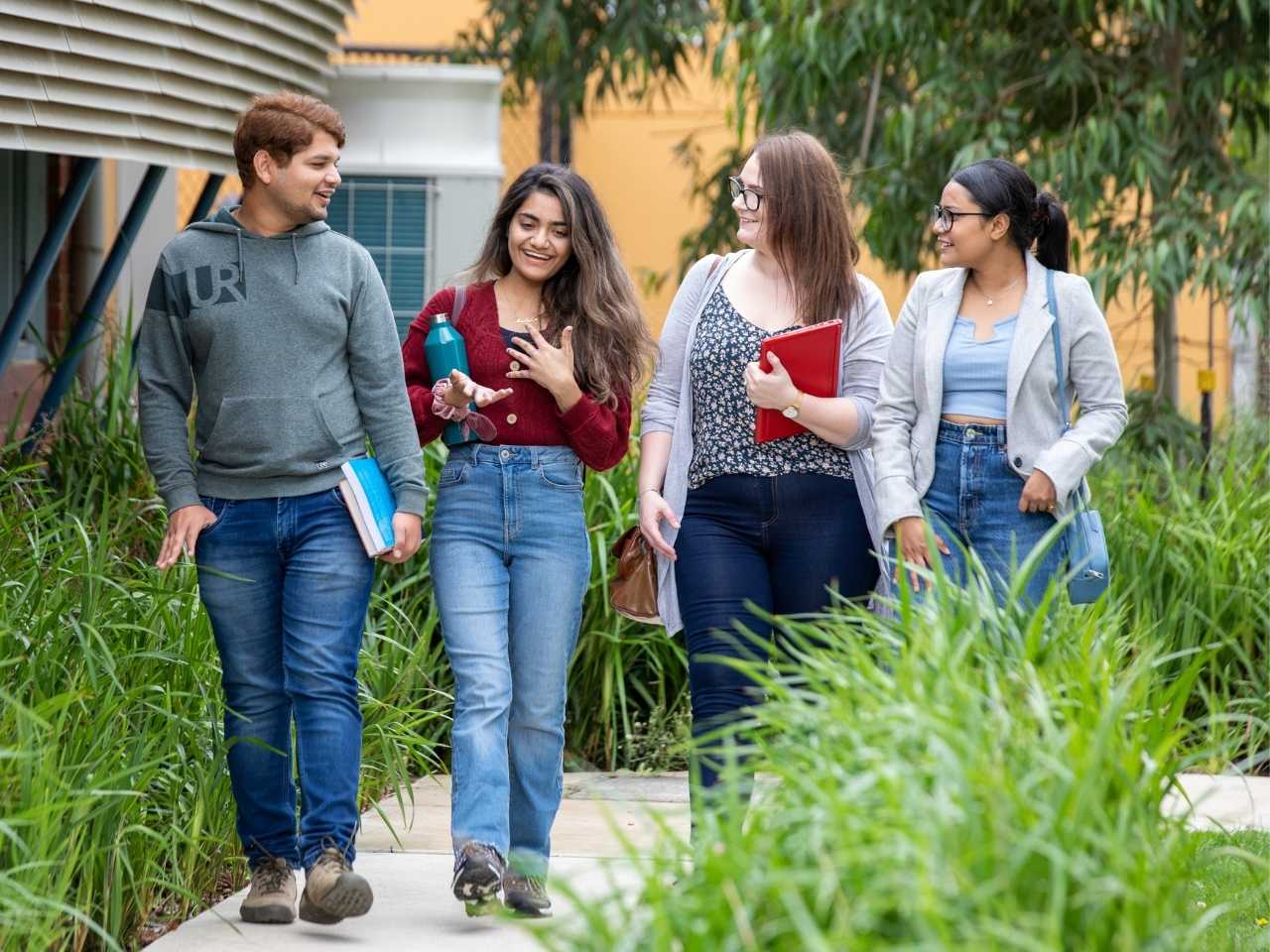 Four students talking together walking on campus